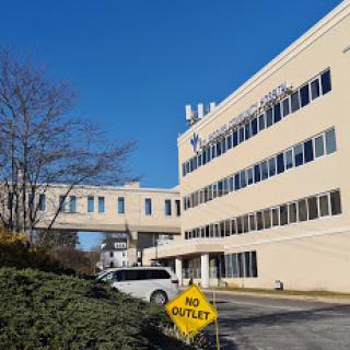 A hospital building with a connecting bridge under a clear blue sky.
