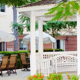 A charming outdoor patio area featuring a white gazebo, surrounded by tables and chairs with umbrellas.