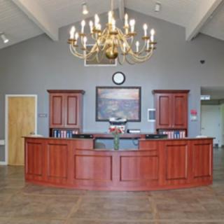 A spacious reception area featuring a wooden desk and a large chandelier.