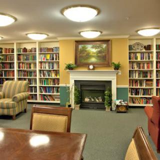 A cozy library with shelves full of books and a fireplace.