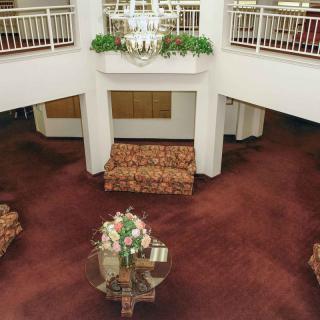 A spacious lobby with elegant furniture, a large chandelier, and decorative plants.