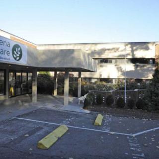 View of a commercial building with clear signage and a landscaped parking area.