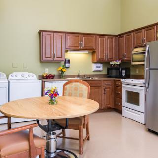 A cozy kitchen showing wooden cabinets, a dining table, and modern appliances.
