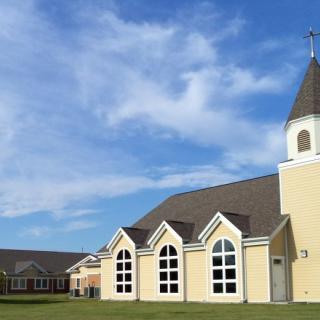 A picturesque church with a steeple under a blue sky with clouds.