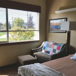 A cozy room featuring a bed, colorful couch, and large window allowing natural light to fill the space.