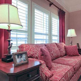 A cozy living room with a patterned sofa, decorative lamps, and elegant red curtains.