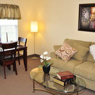 A cozy living room with a sofa, coffee table, dining area, and warm lighting.