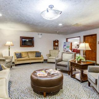 A cozy waiting room with comfortable sofas and armchairs, decorated with lamps and artwork.