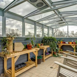 A serene greenhouse filled with potted plants and wooden benches under a glass roof.