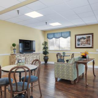 A cozy living room with a television and seating area, featuring stylish decor and indoor plants.