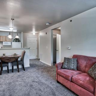 A cozy living area featuring a red sofa and an open kitchen with a dining table.