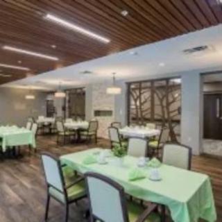 A modern dining area featuring neatly arranged tables with green tablecloths and a stylish wooden ceiling.