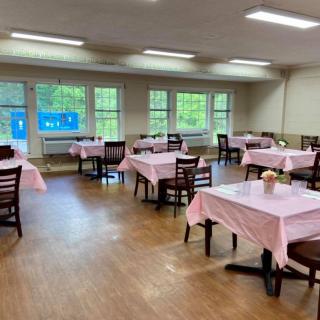 An empty dining room with tables covered in pink tablecloths.