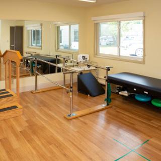 A well-equipped physical therapy room featuring exercise equipment and ample natural light.