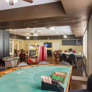 An interior view of a gaming room featuring poker tables and an arcade machine.