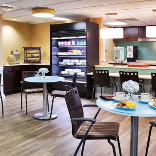 A cozy cafe interior with tables set for breakfast and a well-stocked beverage station.
