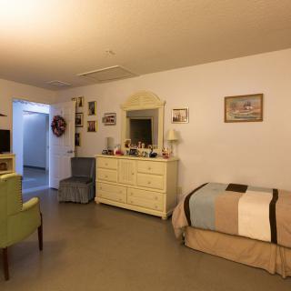 A cozy bedroom with a single bed, a dresser with a mirror, and various decorations on the walls.
