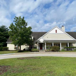 A suburban house with a front porch and surrounding greenery under a cloudy sky.