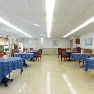 A spacious dining area with blue tablecloth-covered tables and chairs.