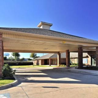 A building entrance with a covered driveway and clear blue sky.