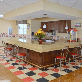 A retro-style kitchen with a checkerboard floor and island counter surrounded by bar stools.