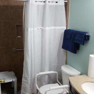 An accessible bathroom setup with a shower curtain, toilet with grab bars, and towels.