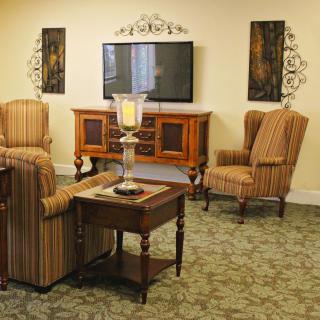 A cozy living room with vintage-style furniture and decor, featuring striped armchairs and a television.