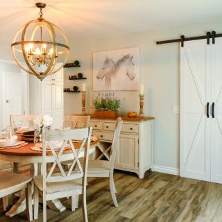 A modern farmhouse dining room with a chandelier, barn door, and wooden furniture.