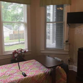 Cozy bedroom with a colorful bedspread and large windows.