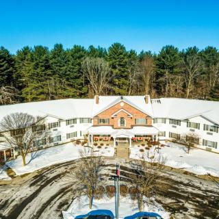 Aerial view of a building surrounded by snow and trees in winter.