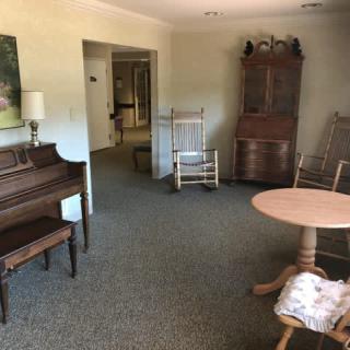 A cozy living room featuring vintage furniture, including a piano and rocking chairs.
