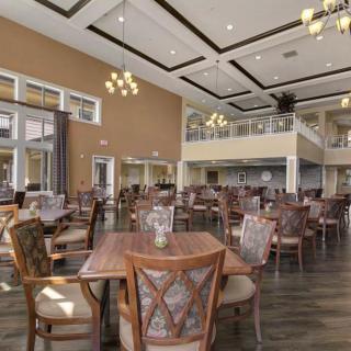 A spacious restaurant dining area with elegant chandeliers and neatly arranged tables and chairs.
