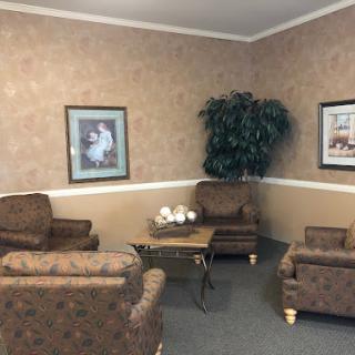 A cozy waiting area featuring comfortable seating, decorative plants, and artwork on the walls.