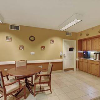 A cozy kitchen area with a round table and chairs, surrounded by cabinets and wall decor.