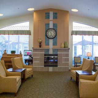 A cozy lobby with comfortable seating, a central fireplace, and large windows letting in natural light.