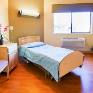 A simple and clean hospital room with a single bed and a window providing natural light.