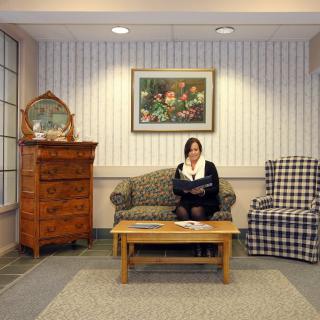 A woman reads on a sofa in a cozy living room with stylish furniture and artwork on the wall.