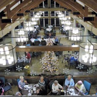 A spacious dining hall adorned with chandeliers and festive decorations, where people are enjoying a meal.
