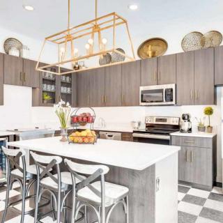 A modern kitchen featuring a spacious island with bar stools, stylish hanging lights, and elegant cabinetry.