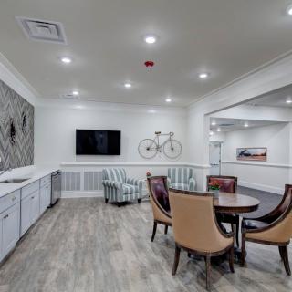 A modern dining area with stylish seating and a wall-mounted television, featuring a decorative bicycle and wood flooring.