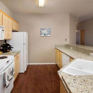 A modern kitchen featuring wood flooring, granite countertops, and various appliances.