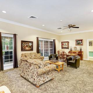 A comfortable living room with patterned furniture, a coffee table, and ample natural light from large windows.