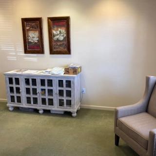 A cozy waiting room with a cabinet and artwork on the wall.
