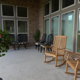 A cozy porch with rocking chairs and additional seating against a brick wall.