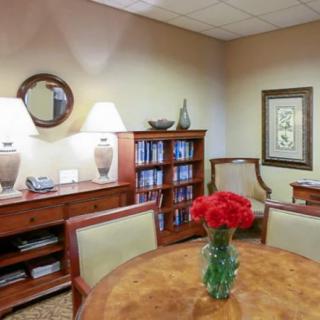 A cozy meeting room with a round table, chairs, bookshelf, and decorative elements.
