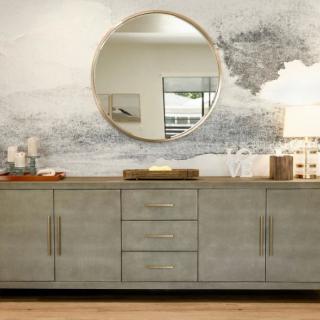 A modern sideboard with a round mirror reflects minimalist interior design aesthetics.