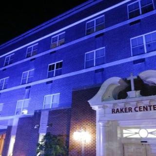 A building illuminated with blue lights at night, featuring a sign that reads 'Baker Center'.