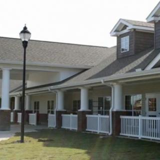 A residential-style building with a porch supported by columns and a gabled roof.