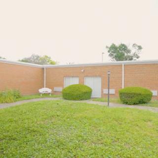 A serene outdoor space featuring a well-maintained lawn and neatly trimmed bushes surrounding a building.