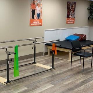 A physical therapy room featuring parallel bars and exercise bands for rehabilitation.